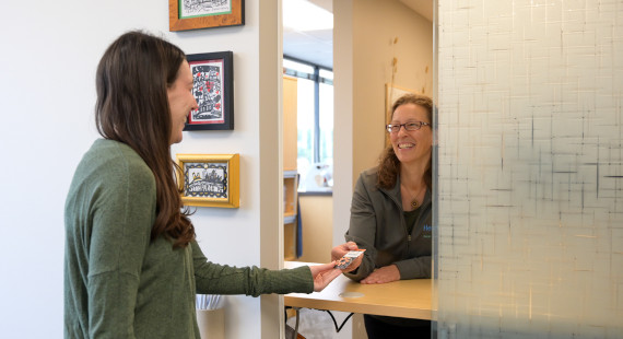 Our team smiles while handing a pack of batteries to a patient